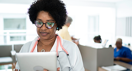 Black female doctor wearing stethoscope looking at a tablet device