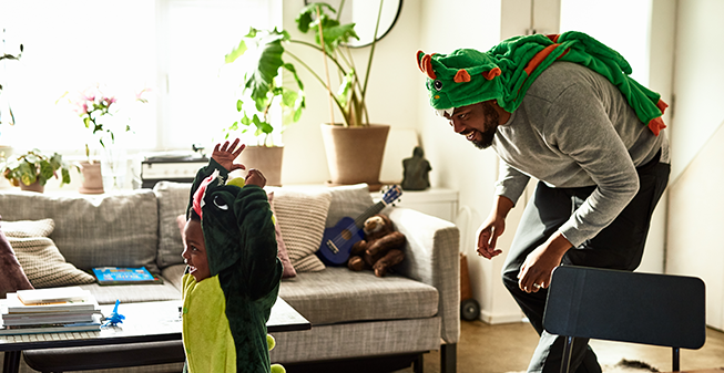 Dad in dinosaur costume chasing son in dinosaur costume