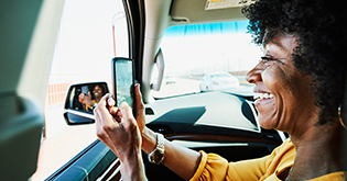 Woman taking a video on her phone from car window